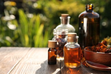 Different tinctures and ingredients on wooden table outdoors, space for text