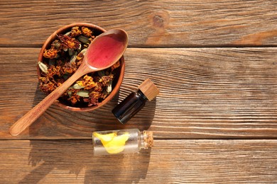 Photo of Tincture, spoon and dried flowers on wooden table, top view. Space for text