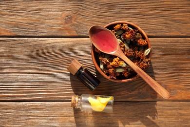 Tincture, spoon and dried flowers on wooden table, top view. Space for text