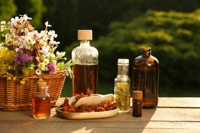 Tincture in bottles and different flowers on wooden table outdoors