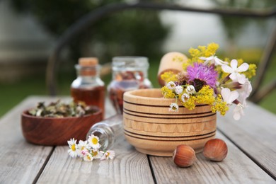 Photo of Different ingredients for tincture, mortar and pestle on wooden bench outdoors