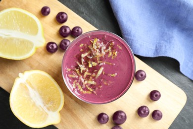 Tasty fresh acai juice in glass with berries and lemon on grey table, flat lay