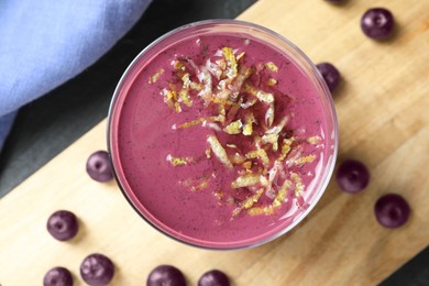 Photo of Tasty fresh acai juice with lemon zest in glass on grey table, top view