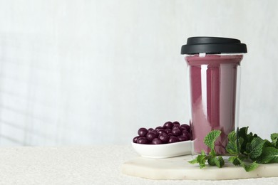 Photo of Tasty fresh acai juice in glass, mint and berries on light textured table, space for text