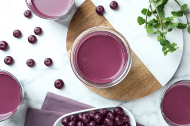 Photo of Tasty fresh acai juice in glasses, mint and berries on white marble table, flat lay