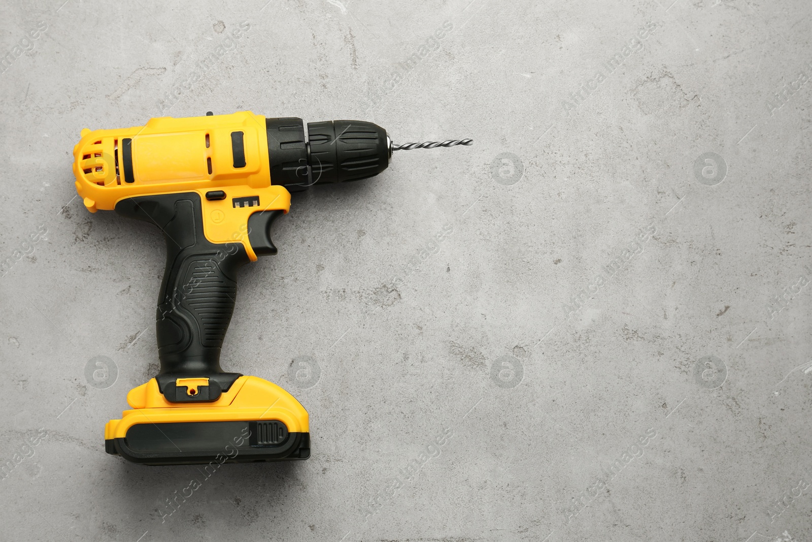 Photo of Modern cordless electric drill on light grey table, top view. Space for text