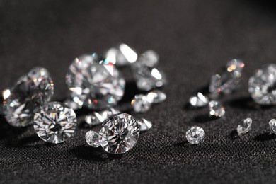 Many beautiful shiny diamonds on black fabric, closeup