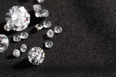 Photo of Many beautiful shiny diamonds on black fabric, closeup. Space for text