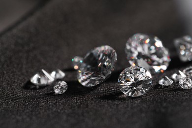 Many beautiful shiny diamonds on black fabric, closeup