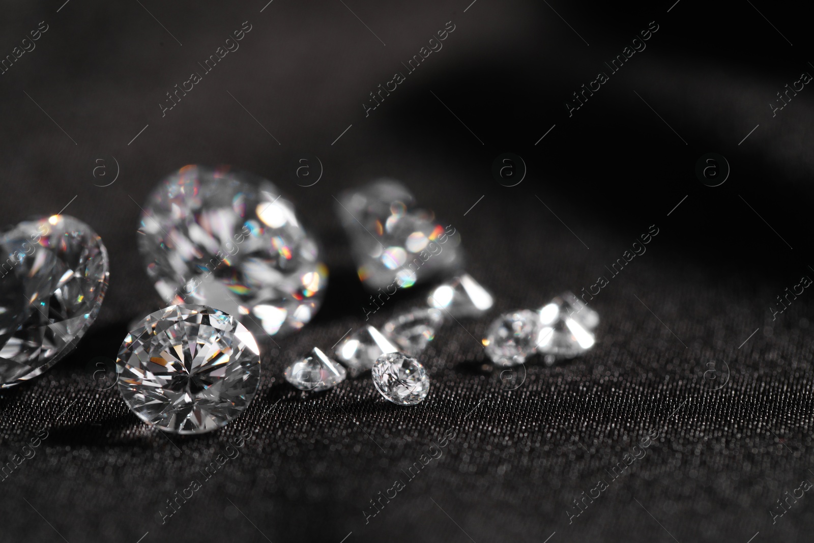 Photo of Many beautiful shiny diamonds on black fabric, closeup