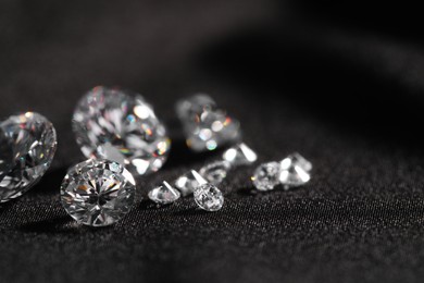 Many beautiful shiny diamonds on black fabric, closeup