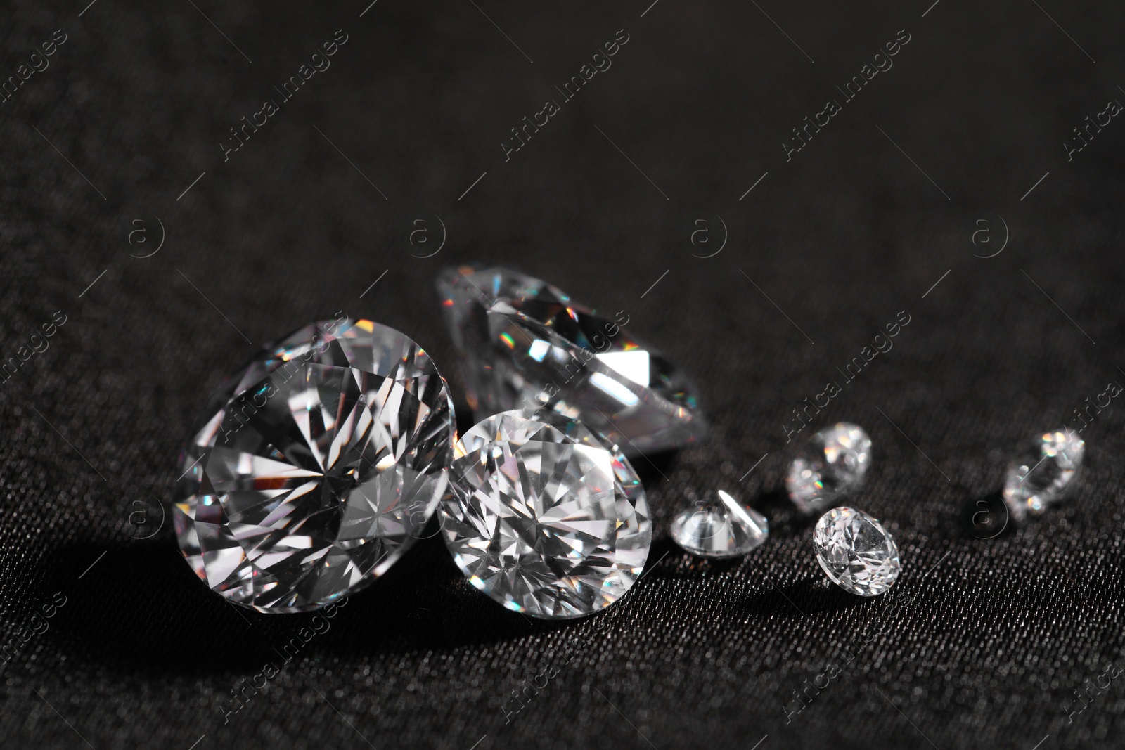 Photo of Many beautiful shiny diamonds on black fabric, closeup