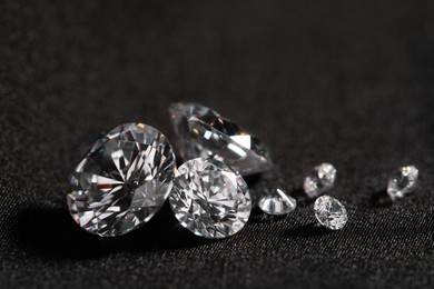 Many beautiful shiny diamonds on black fabric, closeup