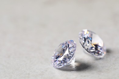 Photo of Two beautiful shiny diamonds on light background, closeup. Space for text