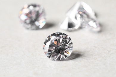 Many beautiful shiny diamonds on light background, closeup