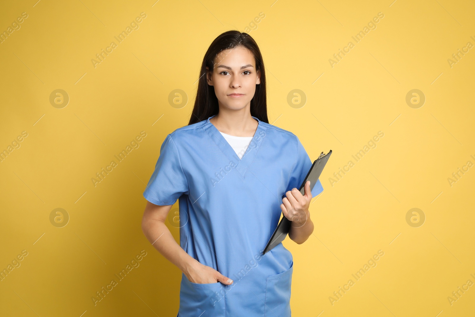 Photo of Portrait of beautiful nurse with clipboard on yellow background