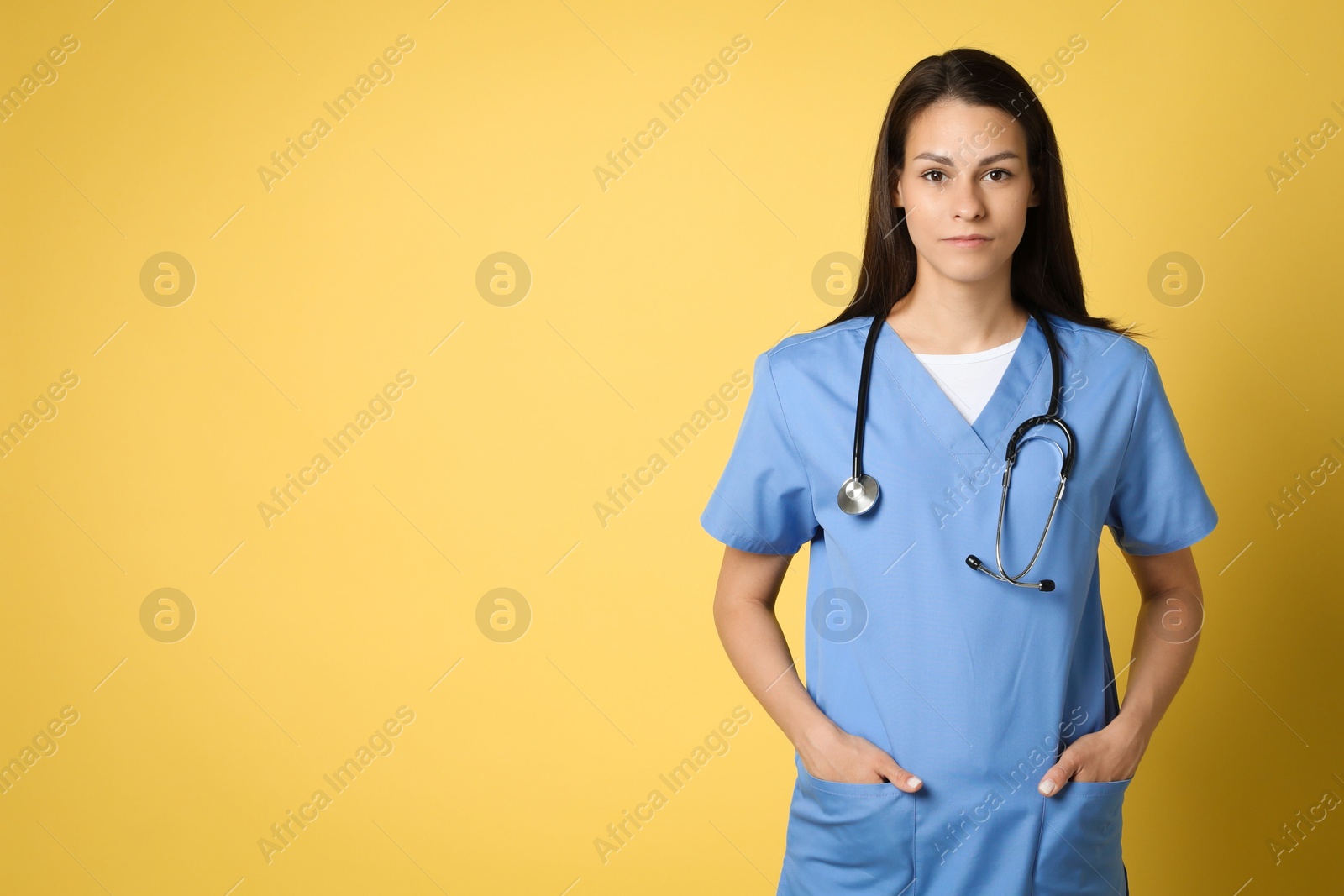 Photo of Portrait of beautiful nurse with stethoscope on yellow background. Space for text