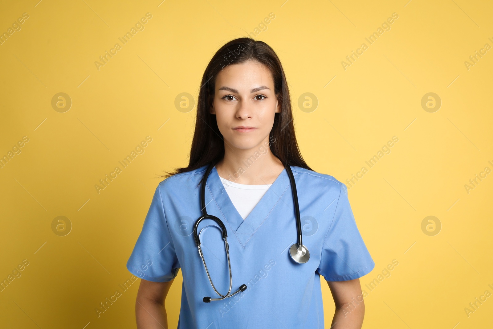 Photo of Portrait of beautiful nurse with stethoscope on yellow background