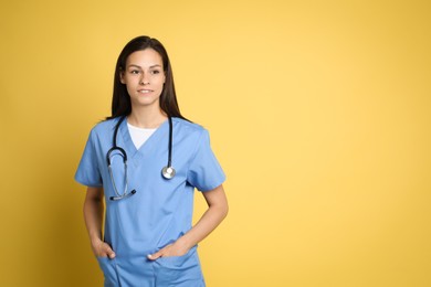 Portrait of smiling nurse with stethoscope on yellow background. Space for text