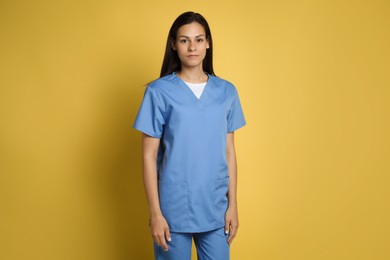 Portrait of beautiful nurse on yellow background