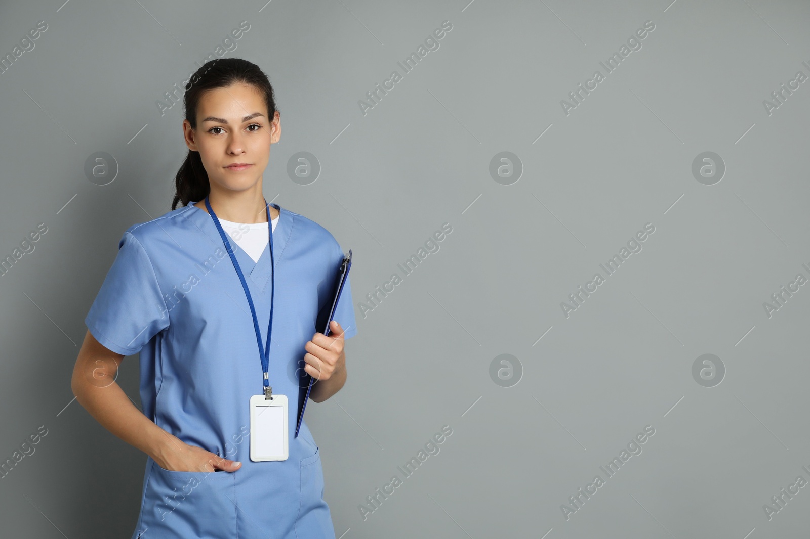 Photo of Portrait of beautiful nurse with clipboard on grey background. Space for text