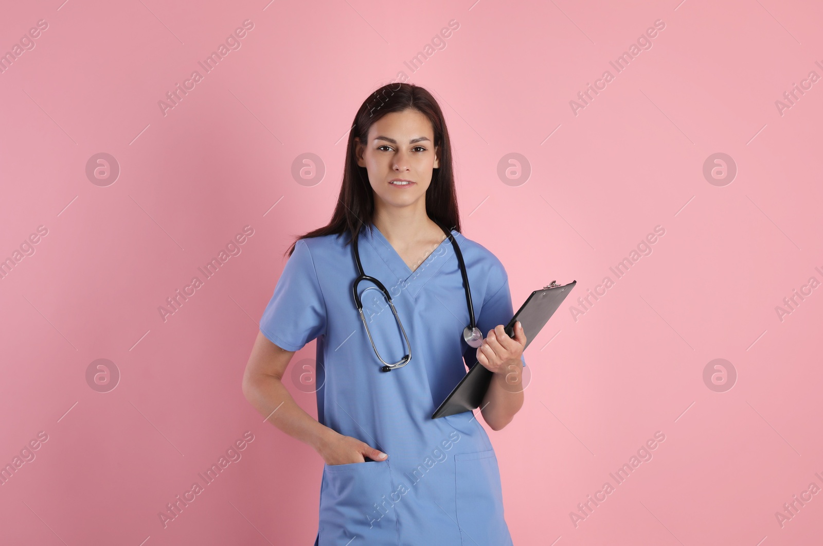 Photo of Beautiful nurse with clipboard on pink background