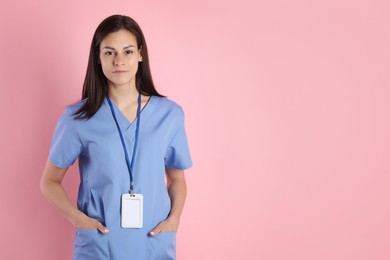 Beautiful nurse with badge on pink background. Space for text