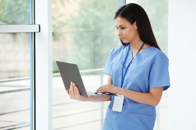 Photo of Beautiful nurse working with laptop in hospital office