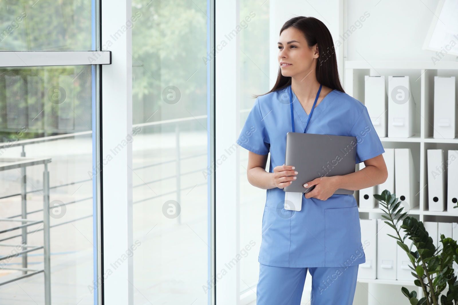 Photo of Smiling nurse with laptop in hospital office. Space for text