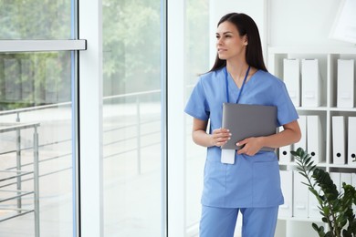 Photo of Smiling nurse with laptop in hospital office. Space for text