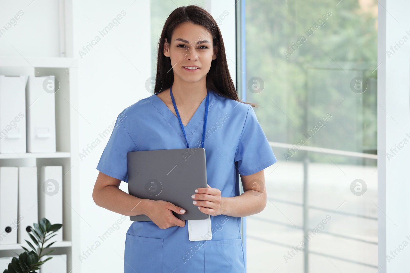 Photo of Smiling nurse with laptop in hospital office