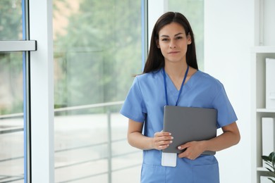 Beautiful nurse with laptop in hospital office. Space for text