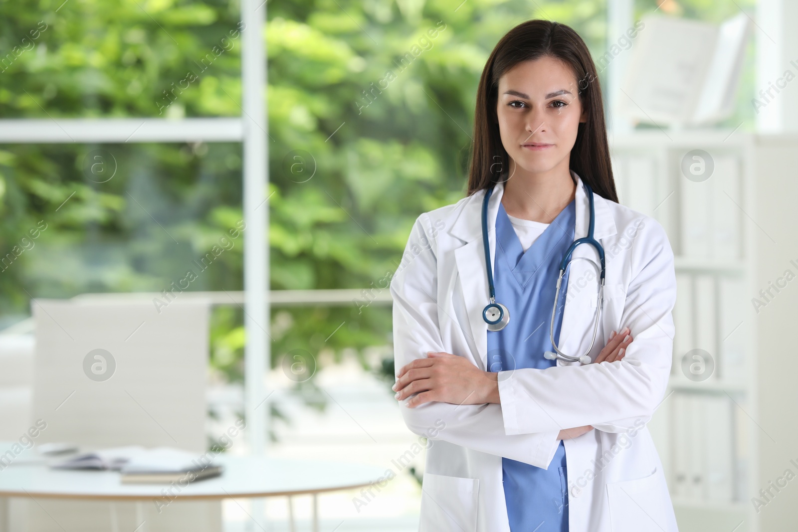 Photo of Beautiful nurse with crossed arms in hospital office. Space for text