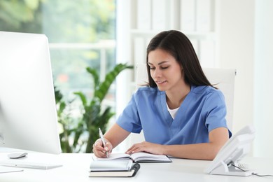 Photo of Beautiful nurse working at table in hospital office