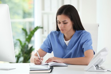 Beautiful nurse working at table in hospital office