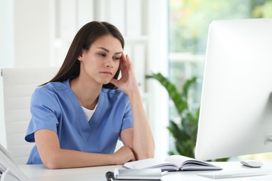 Photo of Tired nurse at table in hospital office