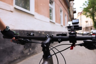 Photo of Man riding bicycle with modern action camera outdoors, closeup