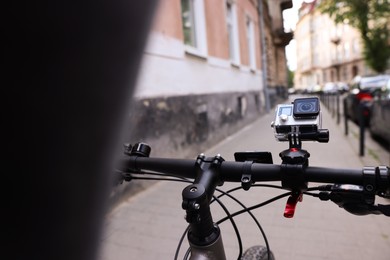 Photo of Man riding bicycle with modern action camera outdoors, closeup