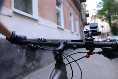 Photo of Man riding bicycle with modern action camera outdoors, closeup