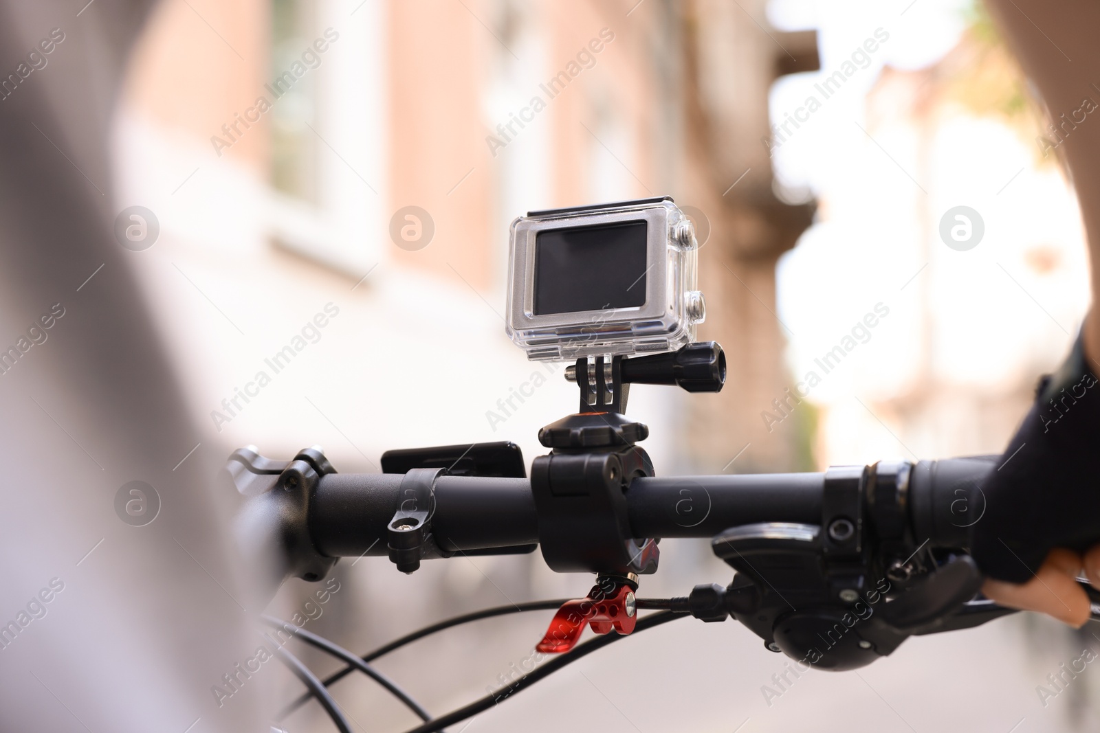 Photo of Man riding bicycle with modern action camera outdoors, closeup