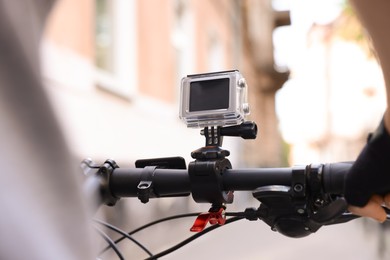 Man riding bicycle with modern action camera outdoors, closeup