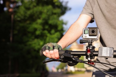 Man riding bicycle with modern action camera outdoors, closeup