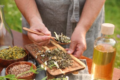 Photo of Senior woman making tincture at table outdoors, closeup