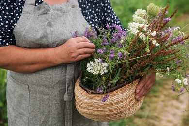 Photo of Senior woman with wildflowers for tincture outdoors, closeup