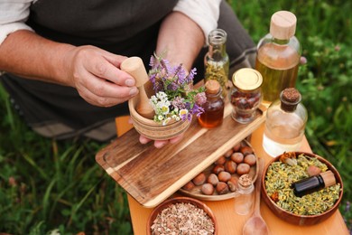 Senior woman with mortar and pestle making tincture outdoors, closeup