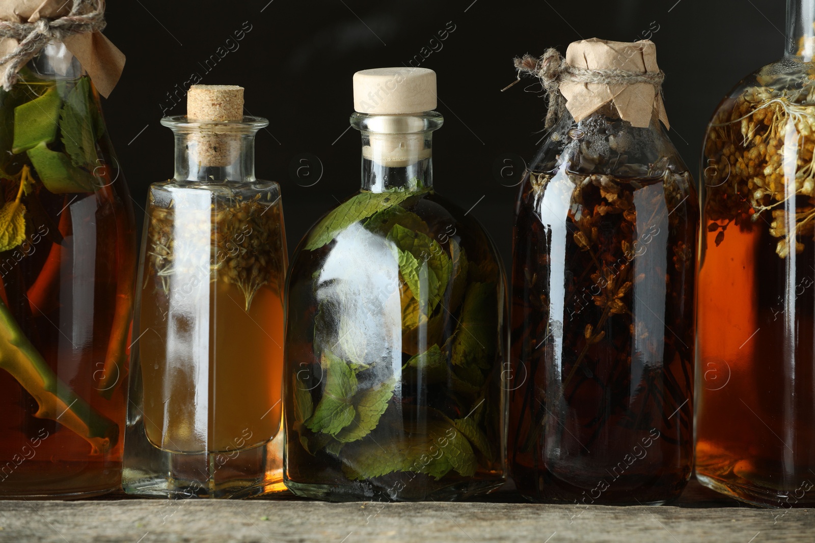 Photo of Different tinctures in bottles on wooden table, closeup