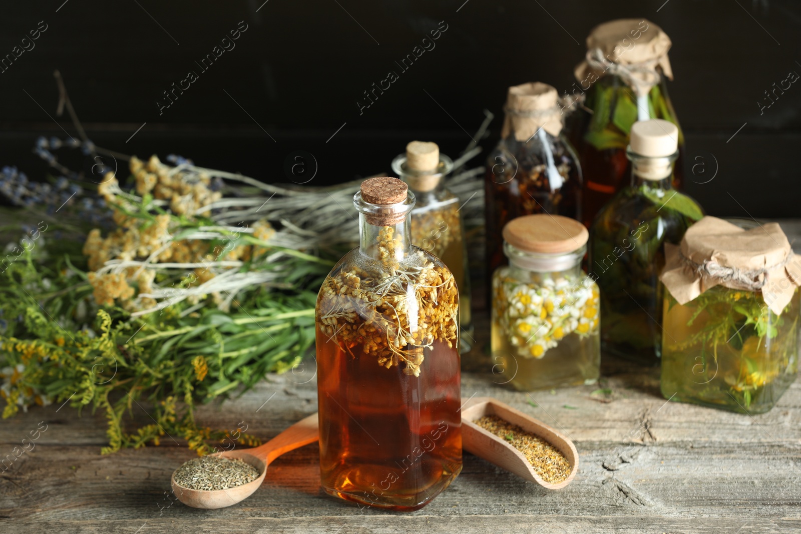 Photo of Different tinctures and herbs on wooden table