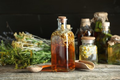 Photo of Different tinctures and herbs on wooden table