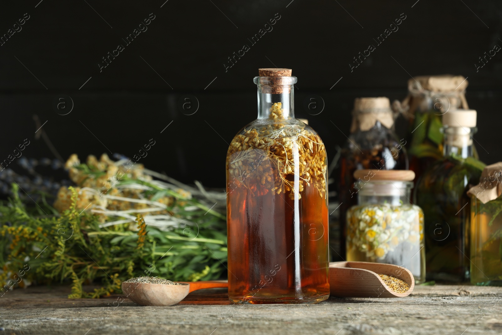 Photo of Different tinctures in bottles and herbs on wooden table