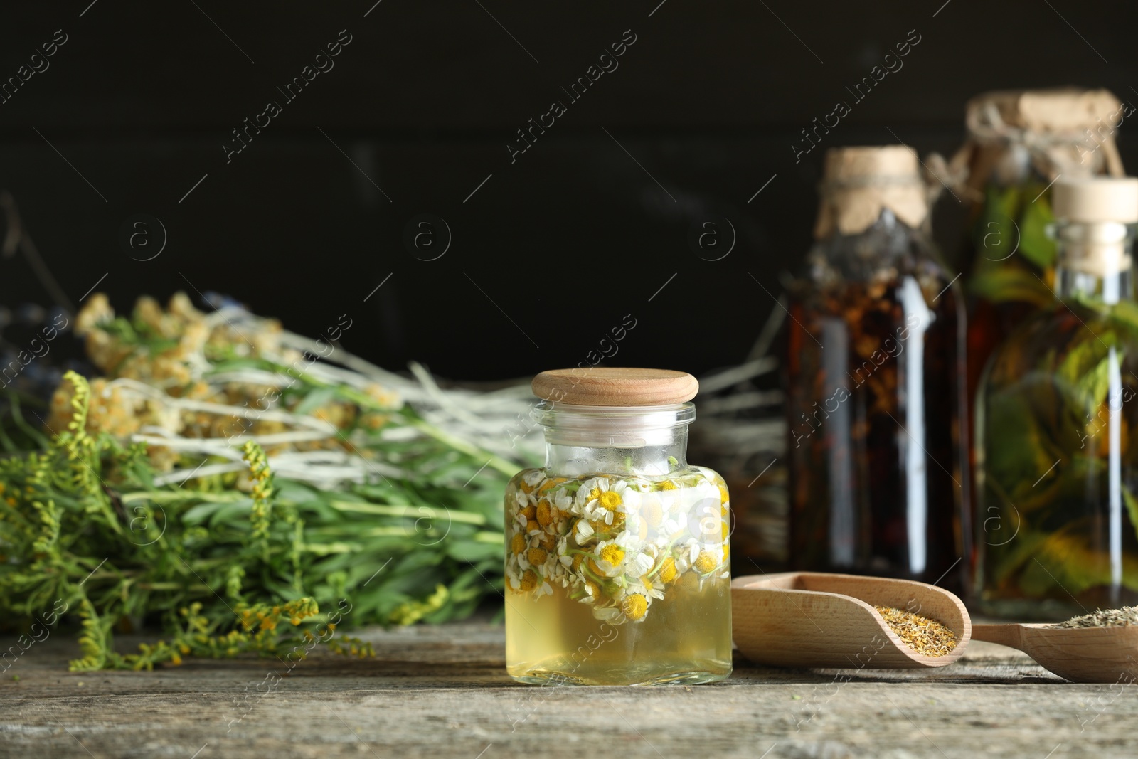 Photo of Different tinctures in bottles and herbs on wooden table